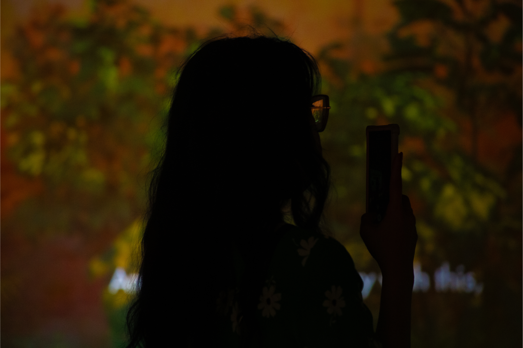 silhouette of a person with long hair holding their phone