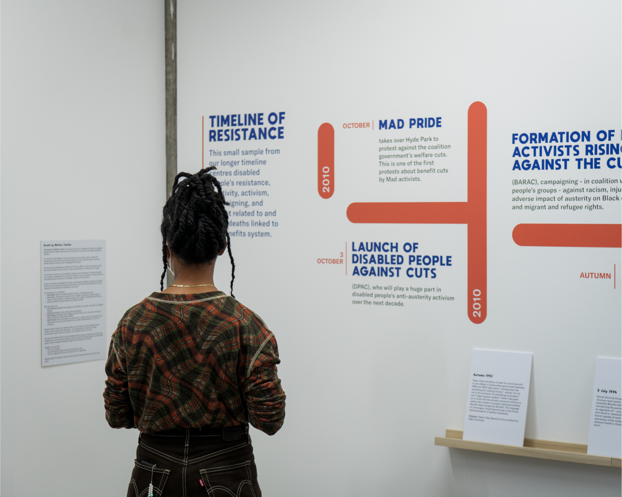person with their back turned looking at the deaths by welfare timeline exhibition