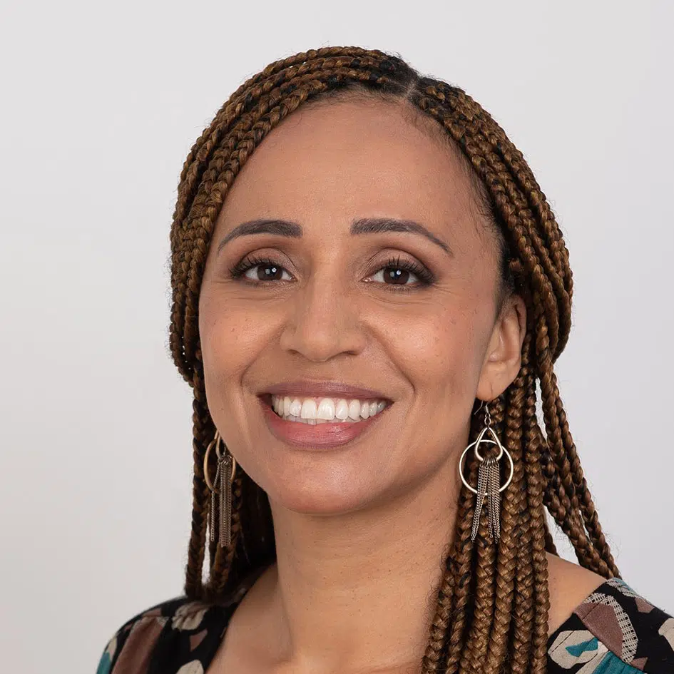 Black woman smiling at the camera with brown braids in her hair