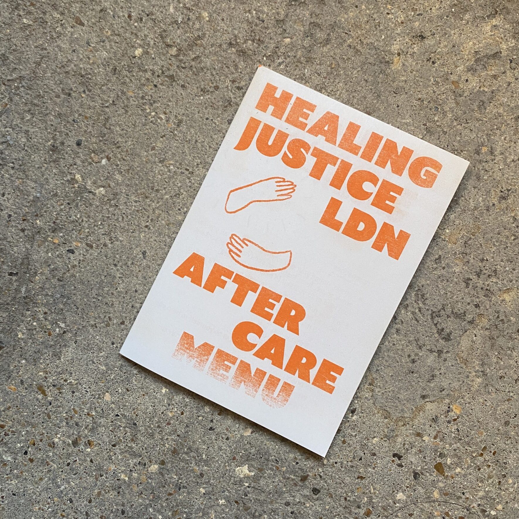 white riso-printed zine sitting on a concrete floor