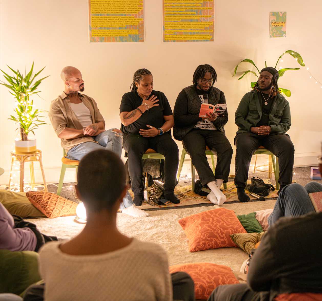 Yomi Sode, Melz Owusu, Marai Larasi and Josh Rivers sitting on chairs in front of a small visible group