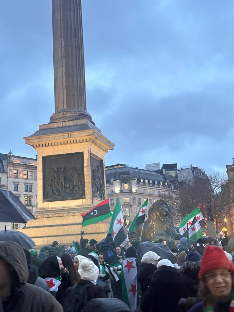 View of Trafalgar square following the fall of Assad A crowd stands in front of Nelson's column with Syrian flags